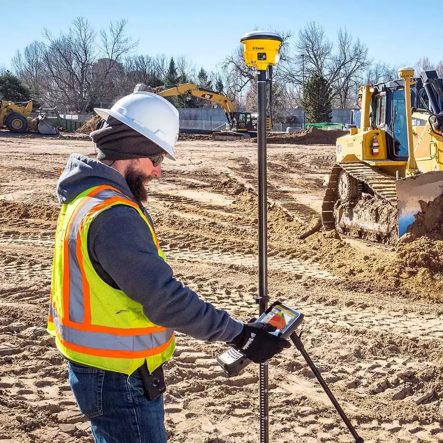 Man in PPE using Machine Guidance with excavator in background