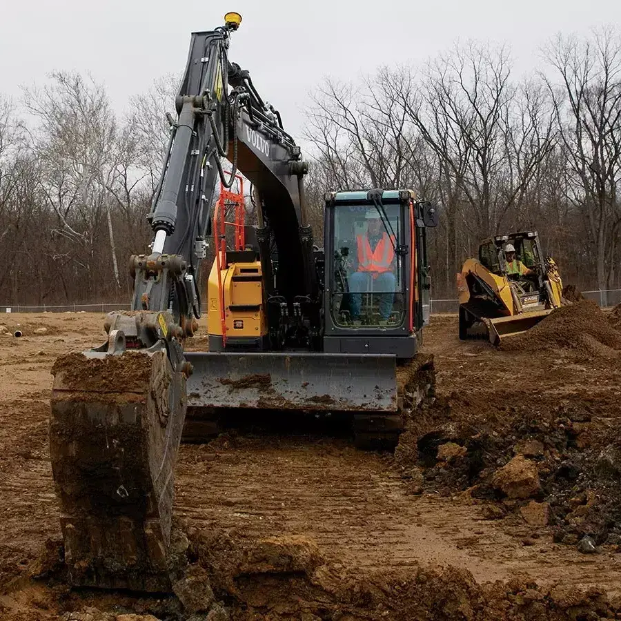 Excavator and compact track loader on work site